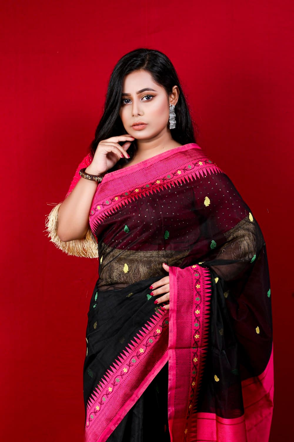 A woman in a black saree with a wide pink border and small woven motifs
