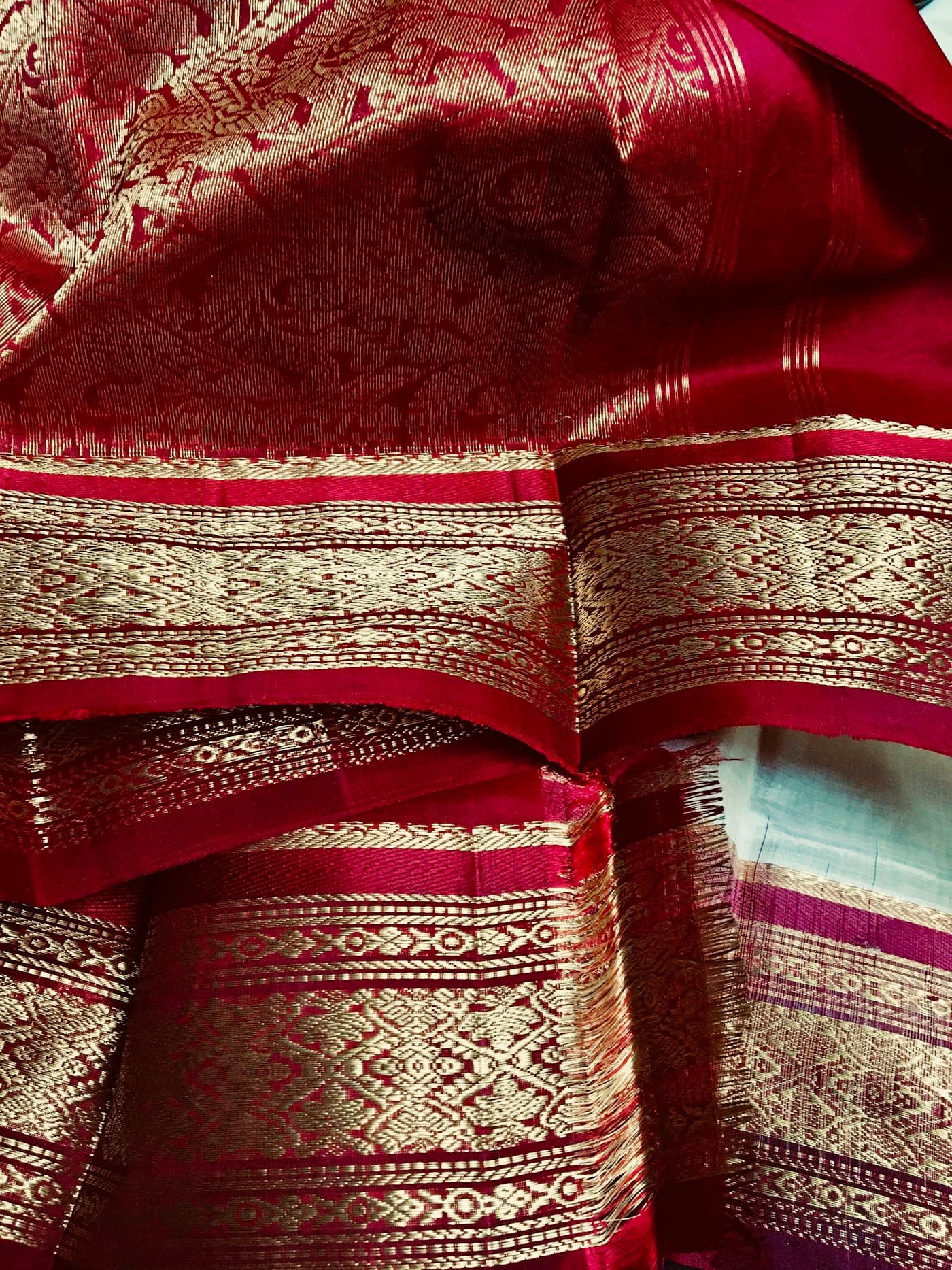 Close-up of folded red silk with wide gold zari borders